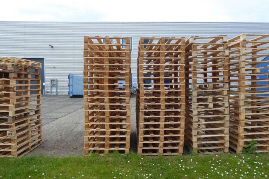 Rows of wooden pallets stacked outdoors near a warehouse, perfect for industrial and logistics themes.
